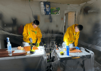 Two painters prepping cabinet doors in a plastic-covered kitchen in Glenview