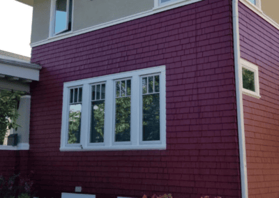 Exterior siding painted deep red with white window trim in Elmhurst