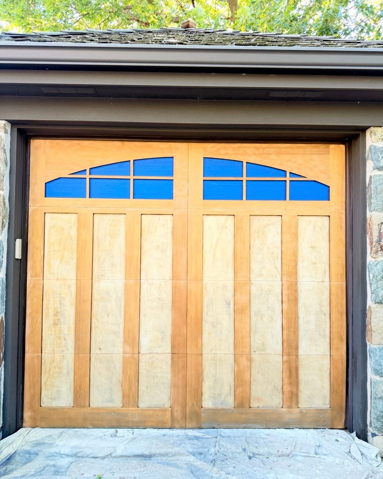 Wood garage door stripped to bare wood in Glenview IL, glass masked in blue before stain application by Sunpainting