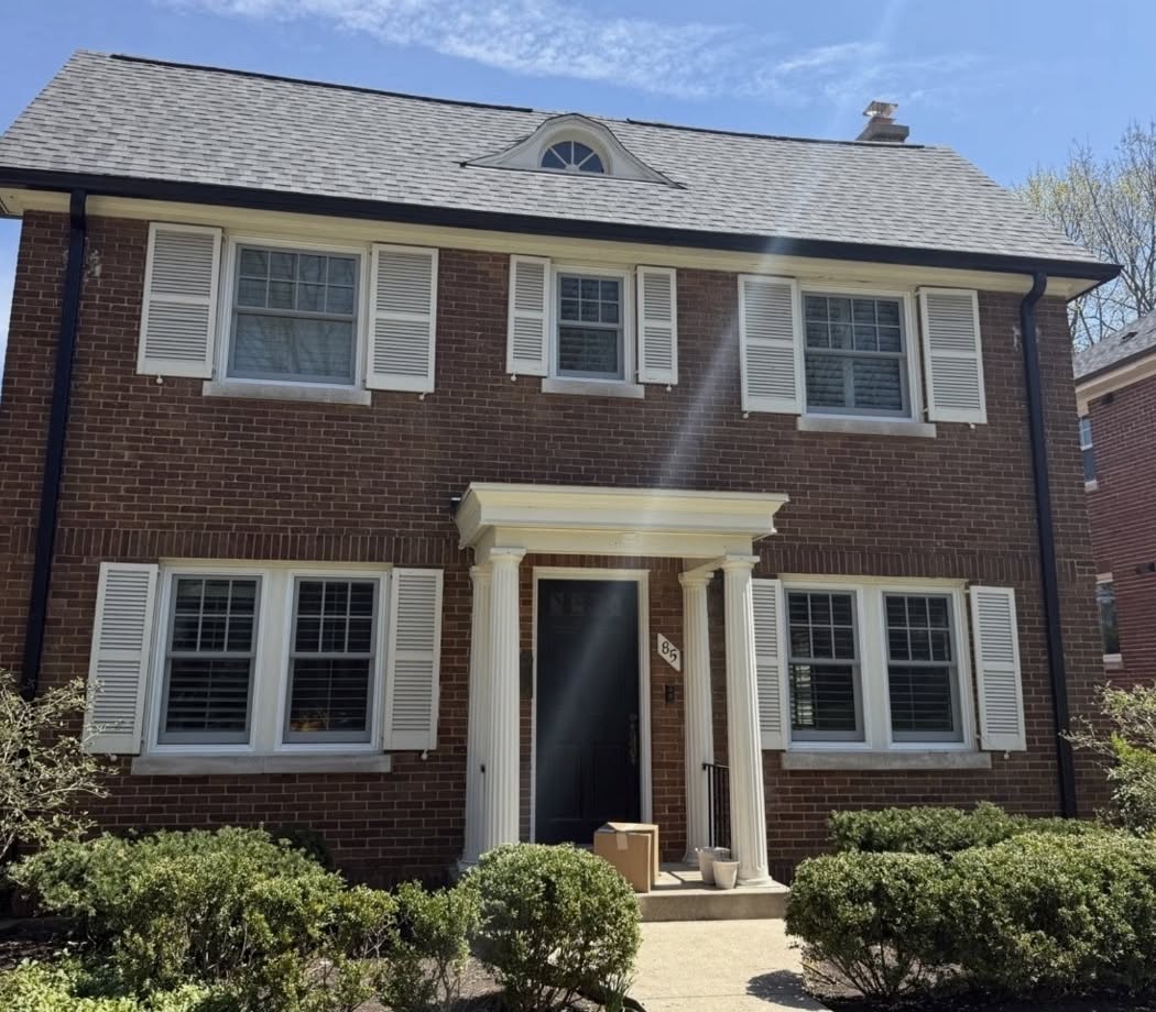 Before exterior painting in Winnetka IL, two-story brick colonial with white shutters, near-black front door, and white downspouts
