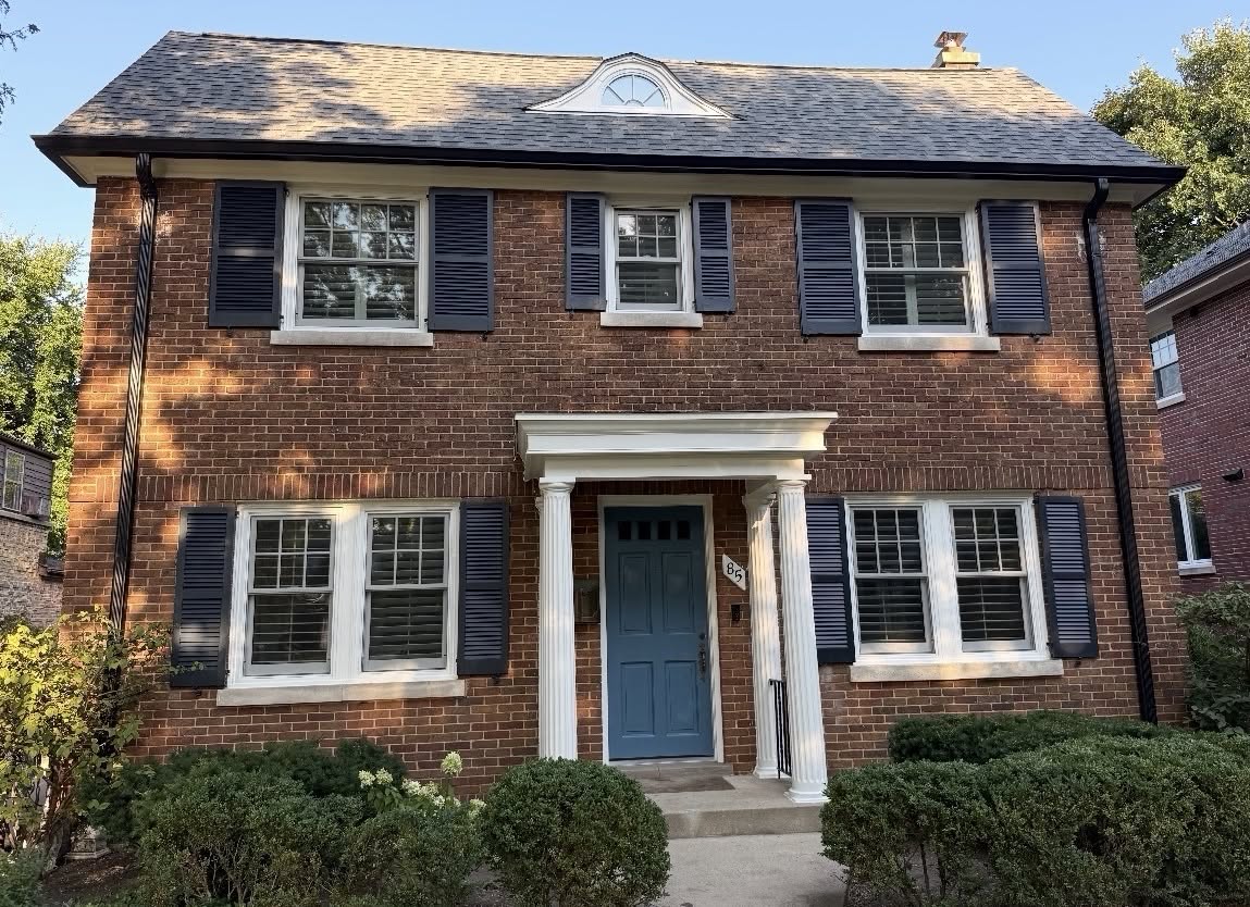 After exterior painting in Winnetka IL by Sunpainting, slate navy shutters and dusty blue front door on a classic red brick colonial