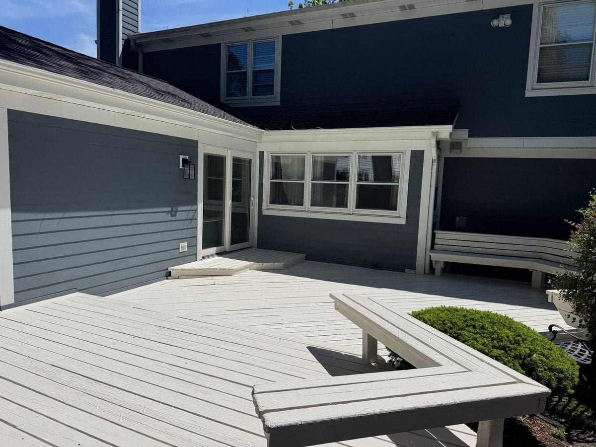 Finished light gray deck with built-in benches in front of a dark gray house