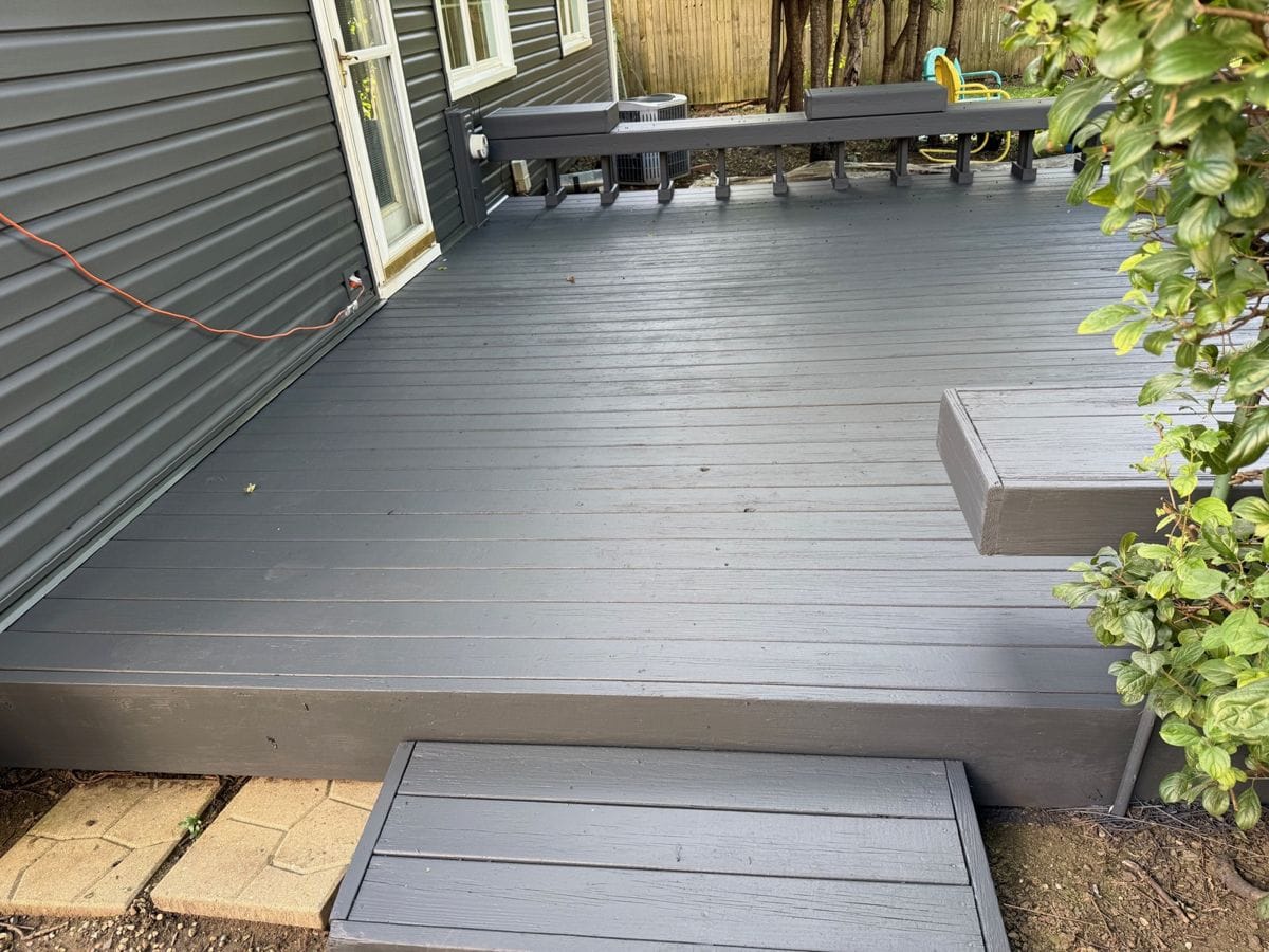 Refinished gray deck with a step and a built-in bench along a dark gray house