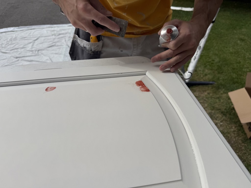 Sunpainting filling and repairing a white cabinet door before painting