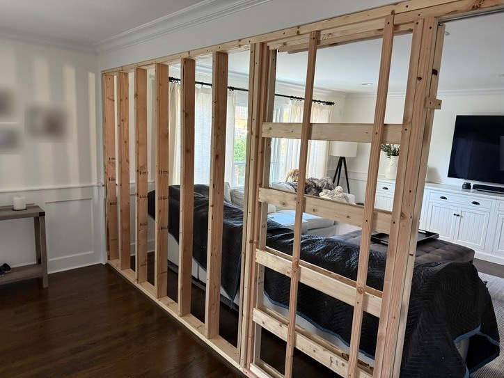 Open-stud wall framing in a living room before drywall