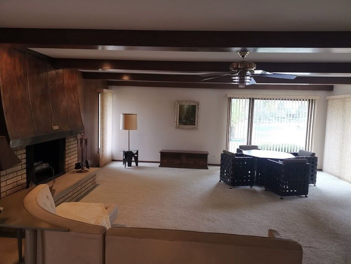 Living room with a dark wood-paneled fireplace wall before paneling removal