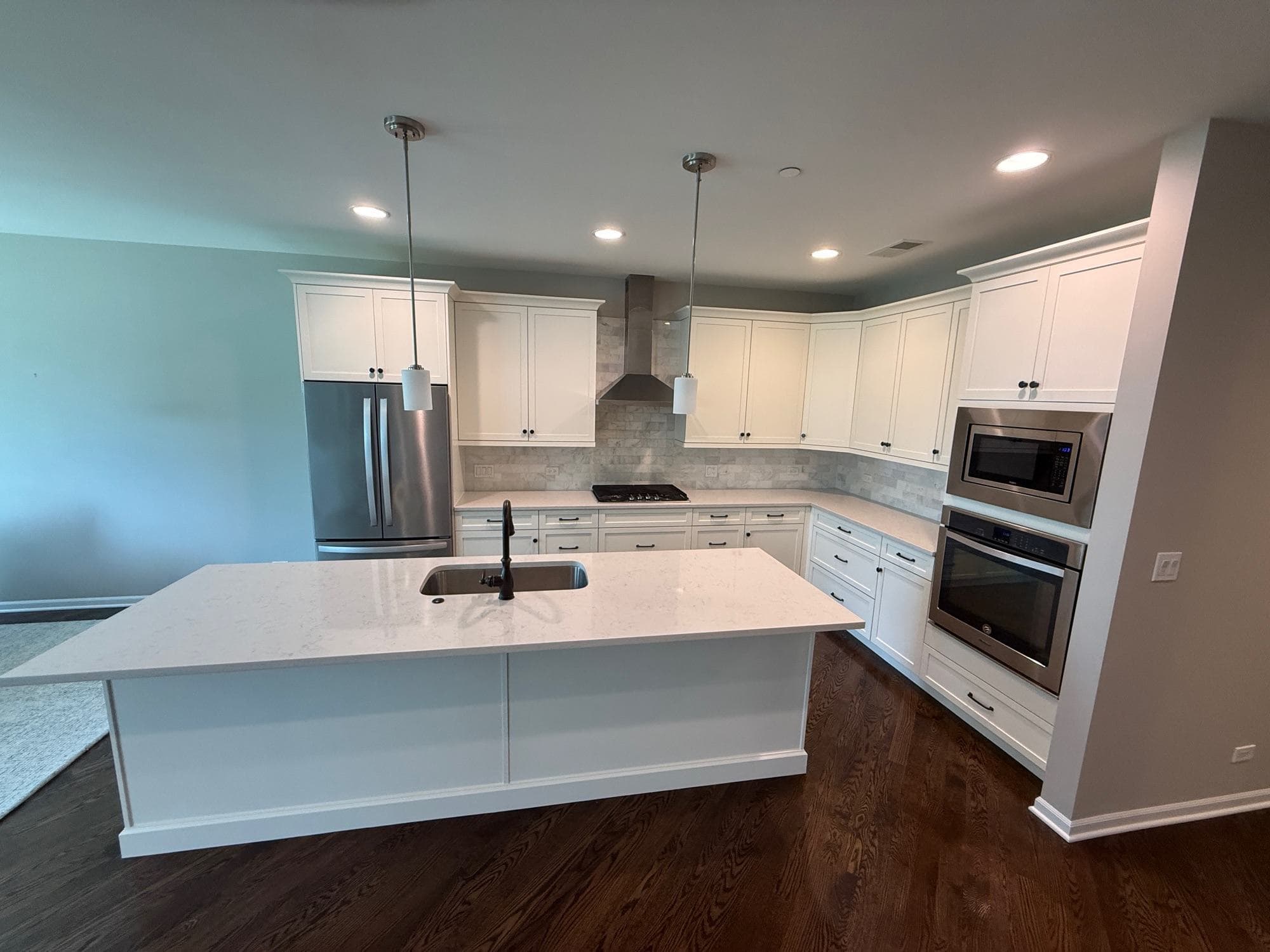 White painted kitchen cabinets and island with dark wood floors by Sunpainting